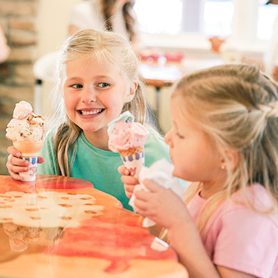 Two young girls eating Over The Top Ice Cream cones and smiling.
