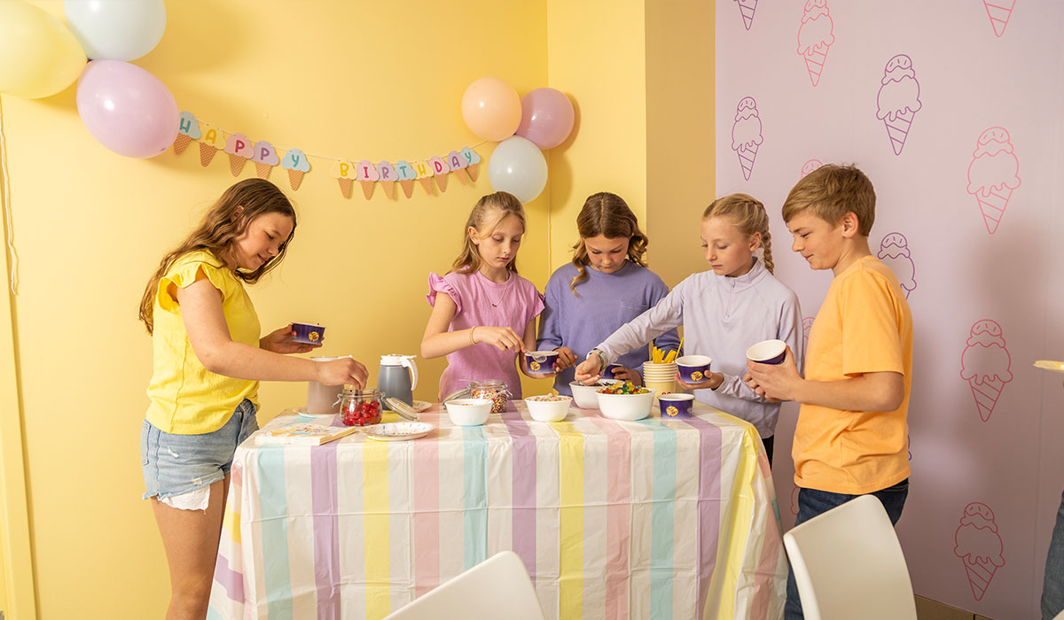 Party room guests at Over The Top Ice Cream at the sundae bar, topping off their scoops with even more treats.