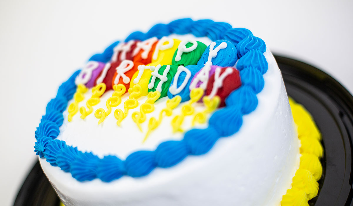 Detail of the 8-inch birthday ice cream cake, featuring rainbow balloons of icing spelling out the words, "HAPPY BIRTHDAY."
