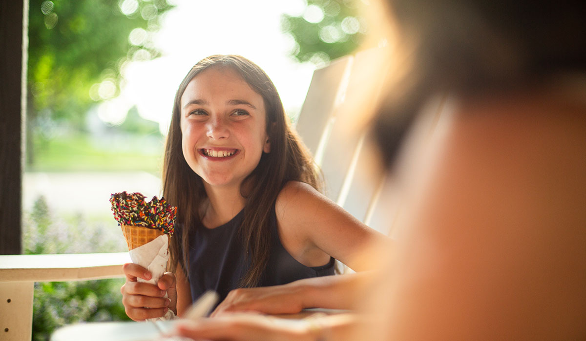 A girl eating ice cream on Over The Top Ice Cream's outdoor patio.