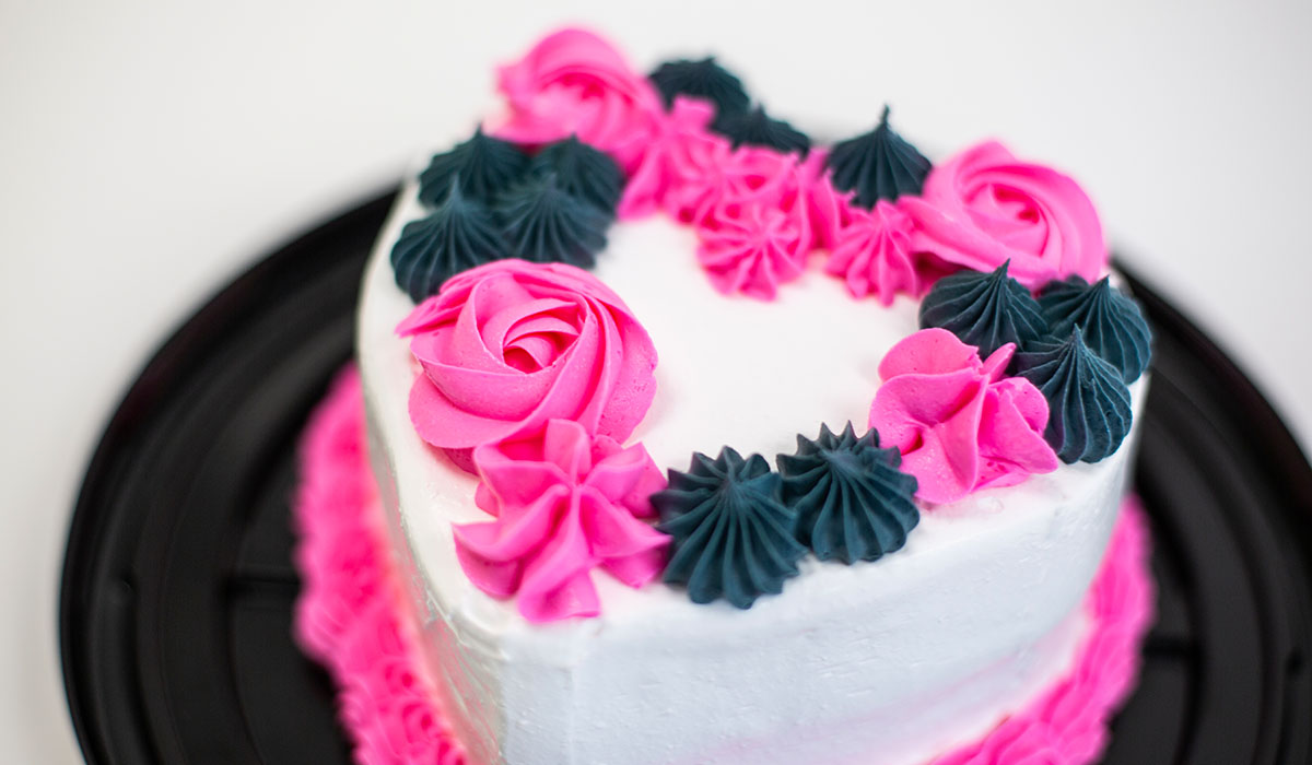 Detail of the bright pink and dark gray floral icing decorations on a 6-inch ice cream cake.